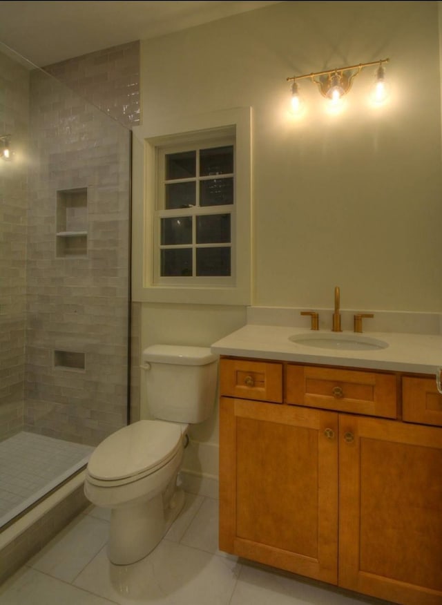 bathroom with tile patterned floors, toilet, vanity, and a tile shower