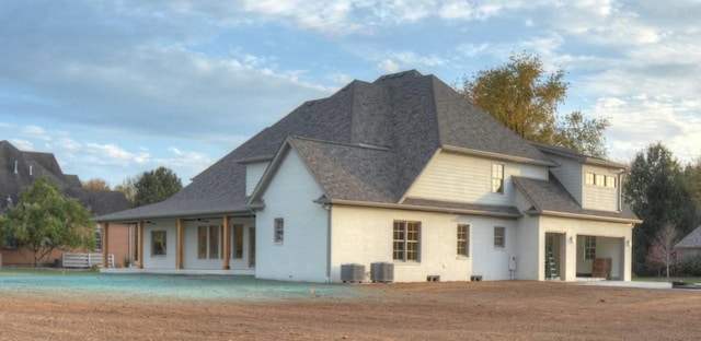 back of property with a garage, a lawn, and central air condition unit