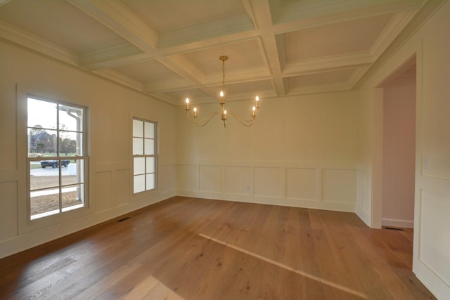 unfurnished dining area featuring hardwood / wood-style flooring, beam ceiling, coffered ceiling, crown molding, and an inviting chandelier