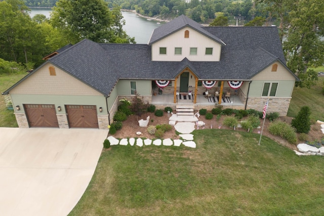 view of front of property with stone siding, covered porch, a front yard, and a water view