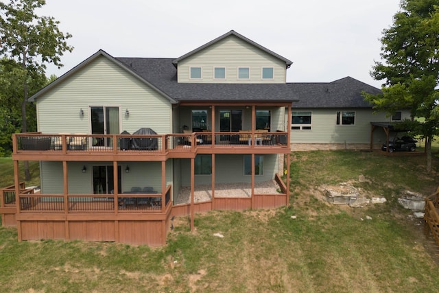 rear view of house with a wooden deck, a lawn, and a shingled roof