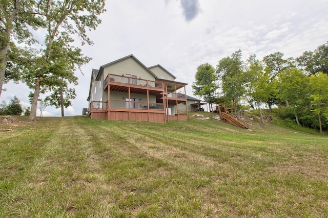 rear view of property featuring stairway, a lawn, and a deck