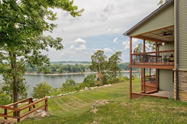 view of yard with a deck with water view and a ceiling fan