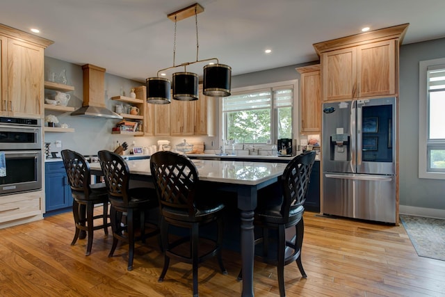 kitchen featuring open shelves, light wood-style flooring, stainless steel appliances, wall chimney range hood, and a center island