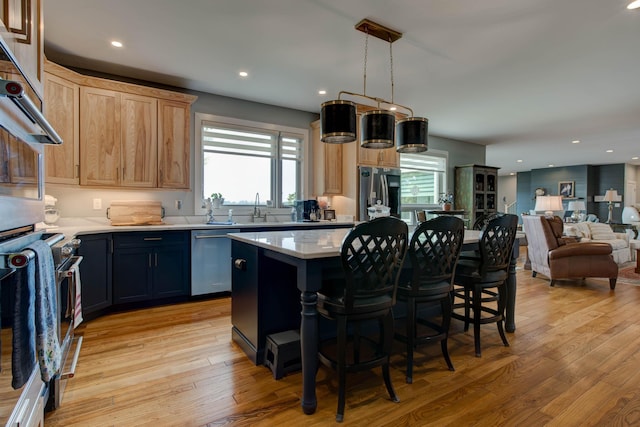 kitchen with light wood finished floors, appliances with stainless steel finishes, a center island, and light countertops