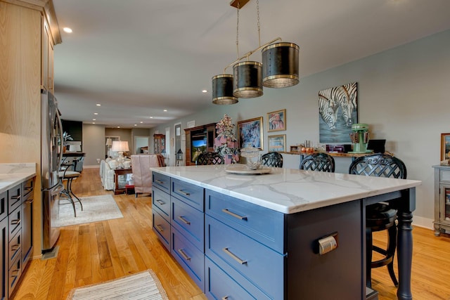 kitchen featuring a kitchen bar, light wood-style floors, open floor plan, and freestanding refrigerator