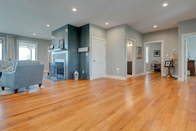 living area featuring recessed lighting, baseboards, a fireplace, and light wood finished floors