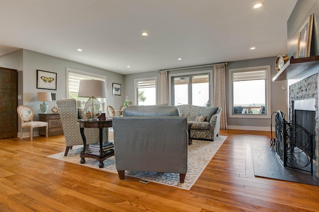 living area with wood finished floors, recessed lighting, a fireplace, and baseboards