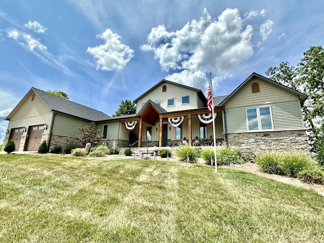 view of front facade featuring stone siding, covered porch, an attached garage, and a front yard