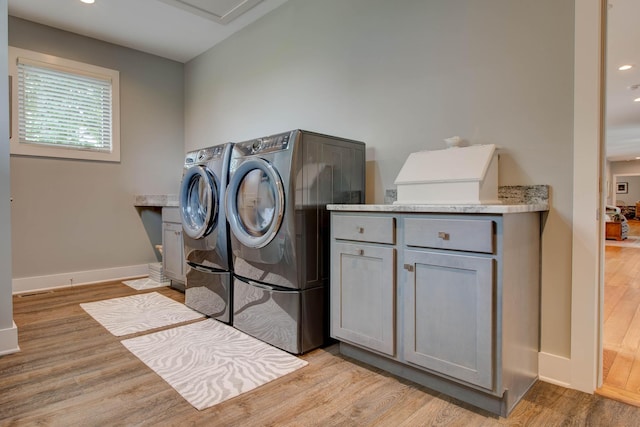 laundry room with cabinet space, separate washer and dryer, light wood-style floors, and baseboards