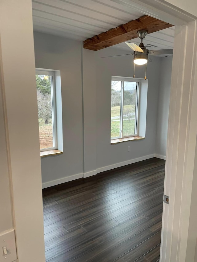 spare room featuring beamed ceiling, dark hardwood / wood-style floors, and a wealth of natural light