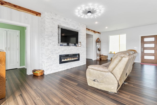 living room with beamed ceiling, a stone fireplace, and dark hardwood / wood-style floors