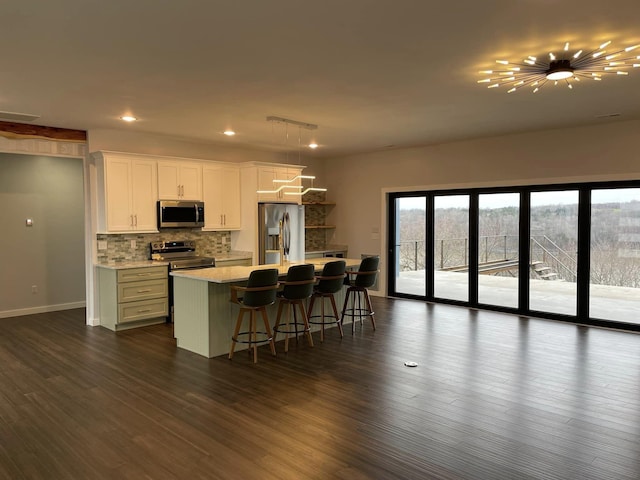 kitchen featuring a kitchen island, white cabinets, a kitchen breakfast bar, decorative backsplash, and stainless steel appliances