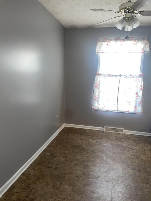 empty room with a textured ceiling and ceiling fan