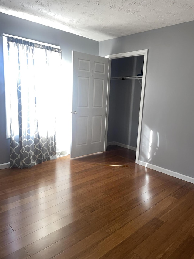 unfurnished bedroom with hardwood / wood-style flooring, a textured ceiling, and a closet