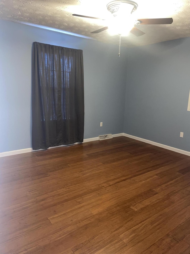 empty room with a textured ceiling, ceiling fan, and dark wood-type flooring