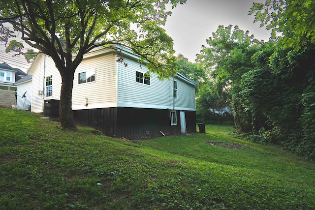 view of property exterior with central AC and a lawn