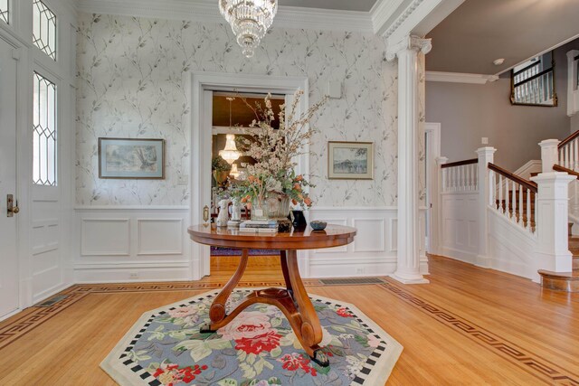 entrance foyer featuring ornamental molding, light hardwood / wood-style flooring, and an inviting chandelier