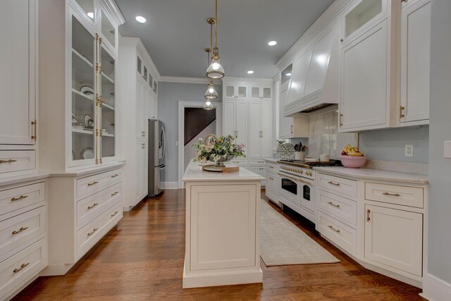 kitchen featuring range with two ovens, wood-type flooring, a center island, custom range hood, and stainless steel refrigerator