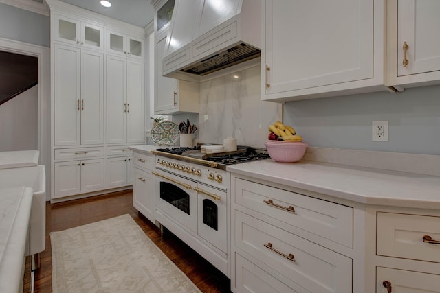 kitchen featuring double oven range, premium range hood, dark hardwood / wood-style flooring, and white cabinets