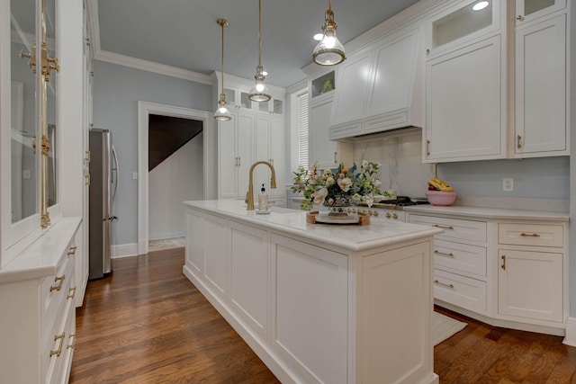 kitchen with stainless steel fridge, an island with sink, white cabinetry, dark hardwood / wood-style flooring, and ornamental molding