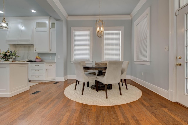 dining area with light wood-style floors, crown molding, and baseboards