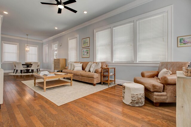 living room with wood-type flooring, crown molding, and ceiling fan