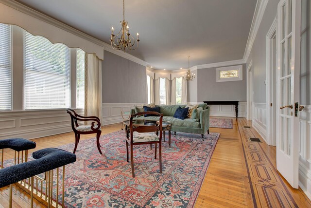 living room with a notable chandelier, light hardwood / wood-style flooring, and crown molding