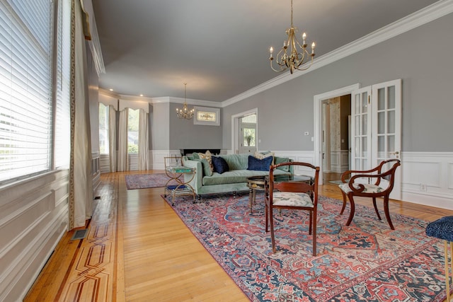 living area with a chandelier, a wainscoted wall, a healthy amount of sunlight, and wood finished floors