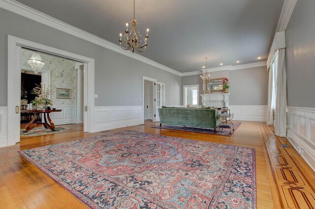 living room featuring an inviting chandelier, light wood-type flooring, and ornamental molding