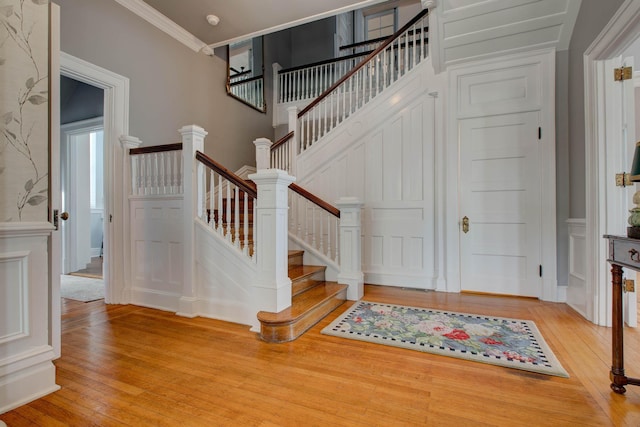 staircase with ornamental molding, hardwood / wood-style floors, and a decorative wall