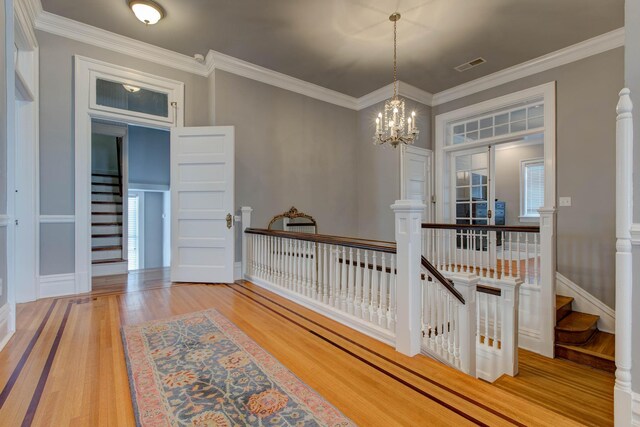 corridor with crown molding, light hardwood / wood-style flooring, and a chandelier