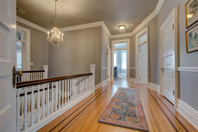 hall featuring crown molding, light wood finished floors, and an upstairs landing