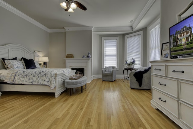 bedroom with crown molding, light wood finished floors, visible vents, a brick fireplace, and baseboards