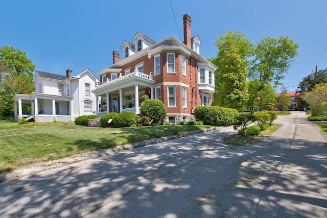 view of front of house with a front yard, brick siding, and a chimney