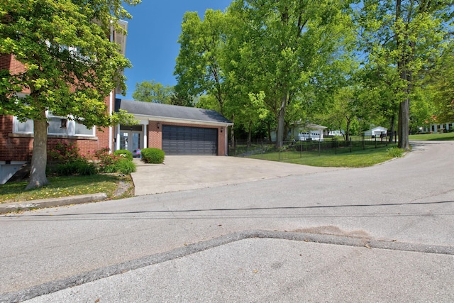 view of front of house with driveway, an attached garage, fence, a front lawn, and brick siding