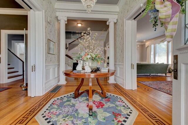 interior space with ornamental molding, decorative columns, and light wood-type flooring