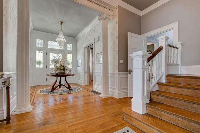 entryway with light hardwood / wood-style floors, ornate columns, and crown molding