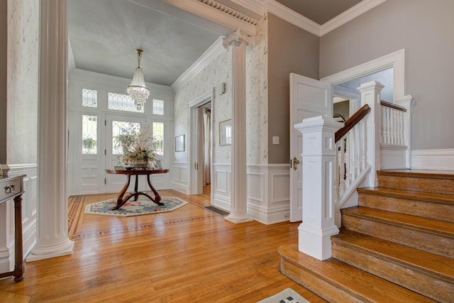 foyer with light wood-style flooring, decorative columns, stairway, and ornamental molding