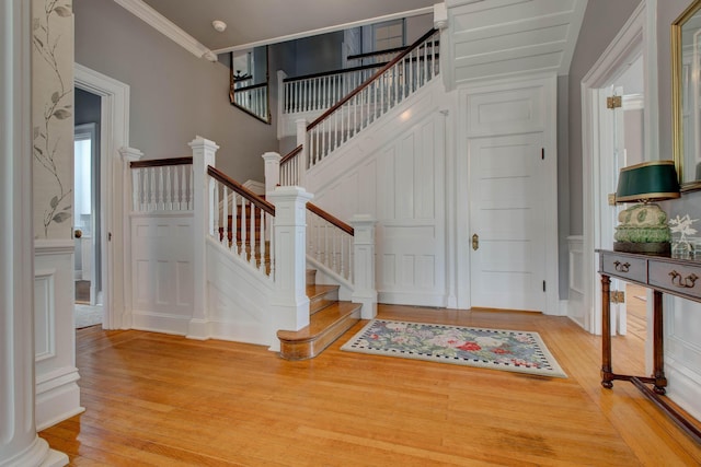 staircase featuring crown molding, a decorative wall, and wood finished floors