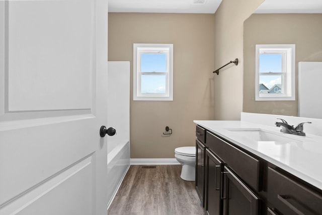 full bathroom featuring hardwood / wood-style flooring, vanity, shower / bath combination, and toilet