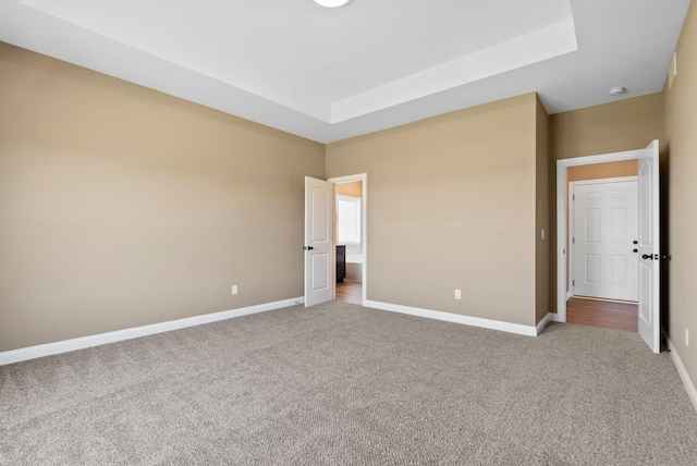 unfurnished bedroom with light carpet and a tray ceiling