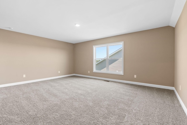 spare room featuring carpet and lofted ceiling