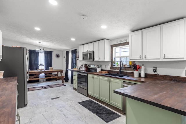 kitchen featuring light tile patterned flooring, white cabinetry, green cabinetry, appliances with stainless steel finishes, and sink