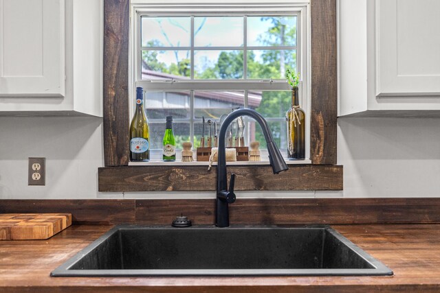 details with white cabinetry, butcher block countertops, and sink