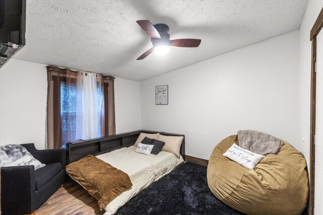 bedroom featuring ceiling fan, wood-type flooring, and a textured ceiling