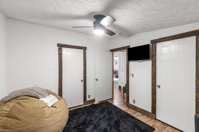 living area with a textured ceiling, hardwood / wood-style floors, and ceiling fan