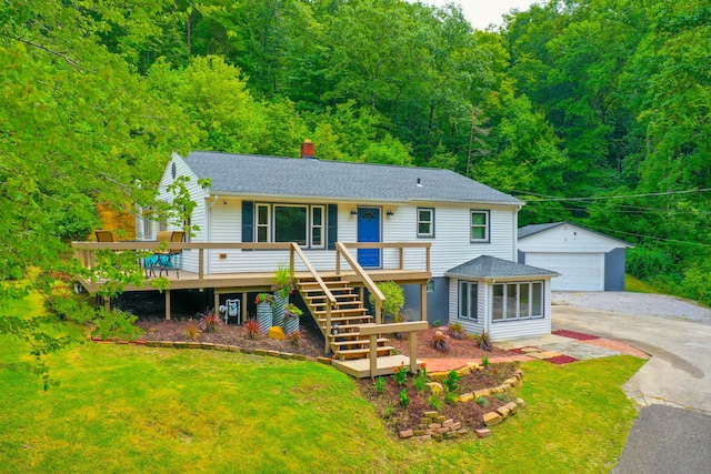 view of front of property featuring a deck, a front lawn, a garage, and an outbuilding