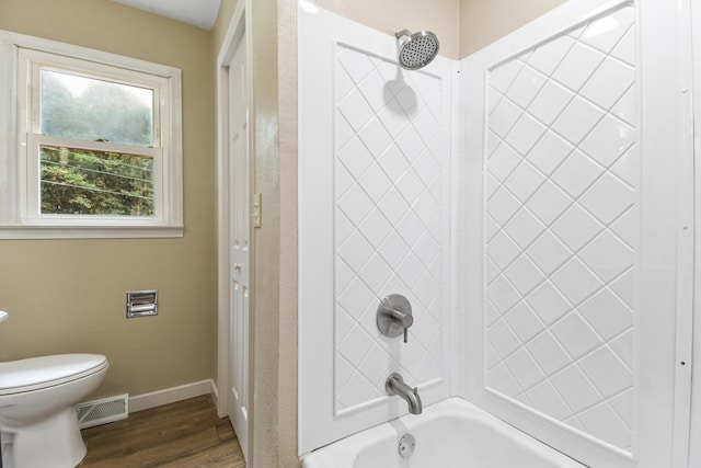 bathroom with hardwood / wood-style flooring, shower / bathtub combination, and toilet