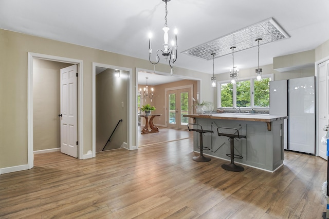 kitchen with a kitchen breakfast bar, french doors, an inviting chandelier, and pendant lighting